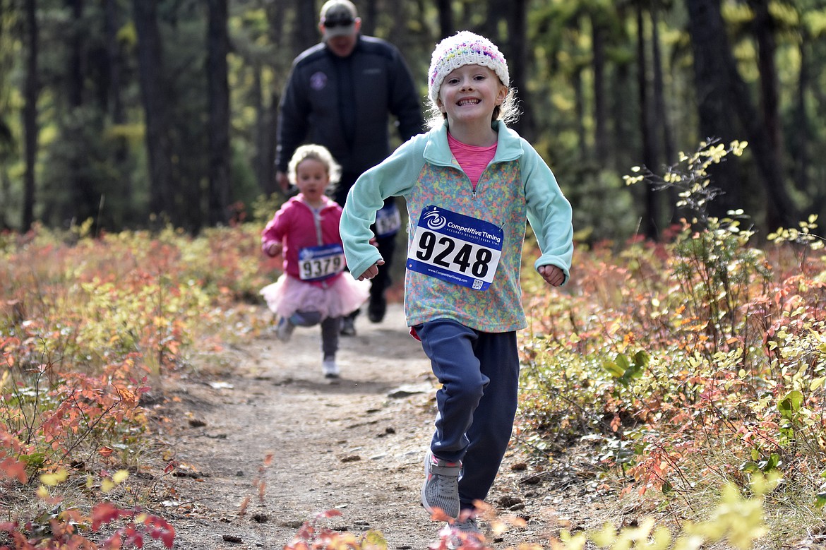 Harper Mulholland, 6, is alls smiles as she runs in the 2-mile fun run on the Whitefish Trail Sunday morning during the Whitefish Trail Legacy Run. (Heidi Desch/Whitefish Pilot)
