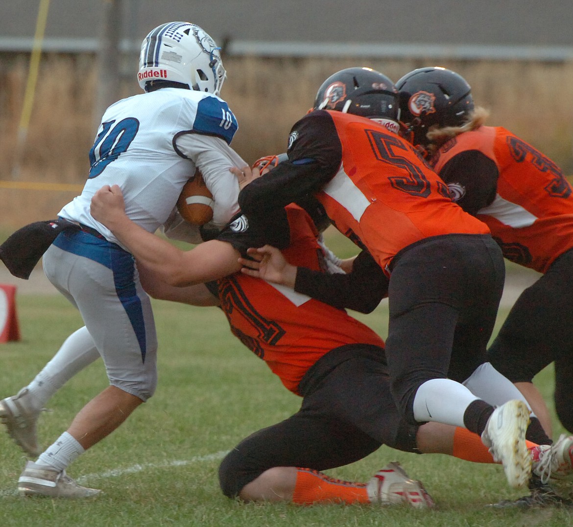 Plains defenders Rusty Stuart (67), Tucker Foster (55) and Malachi Paulsen (30) team up to tackle Mission quarterback Isaac Dumontier during the Horsemen Homecoming game Friday night. The Bulldogs rallied for a 44-40 victory. (Joe Sova photos/Clark Fork Valley Press)
