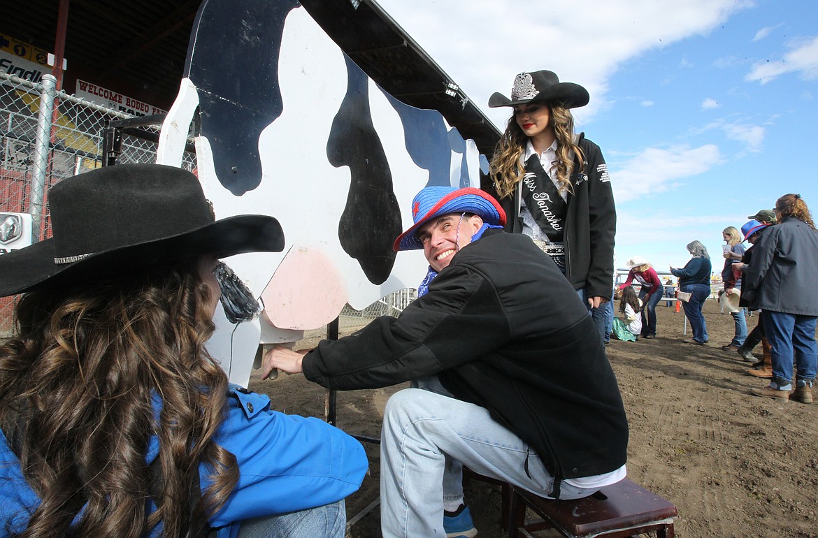 Richard Tritto of Rathdrum can't help but smile as he &quot;milks&quot; a model cow during the Rascal Rodeo at the Kootenai County Fairgrounds on Saturday morning, assisted by Pend Orielle County Queen Emily Sprague, left, and Miss Tonasket Madyson Clark. About 50 special needs participants enjoyed the Rascal Rodeo, where they interacted with horses, rode barrel bulls and made many new friends. (DEVIN WEEKS/Press)