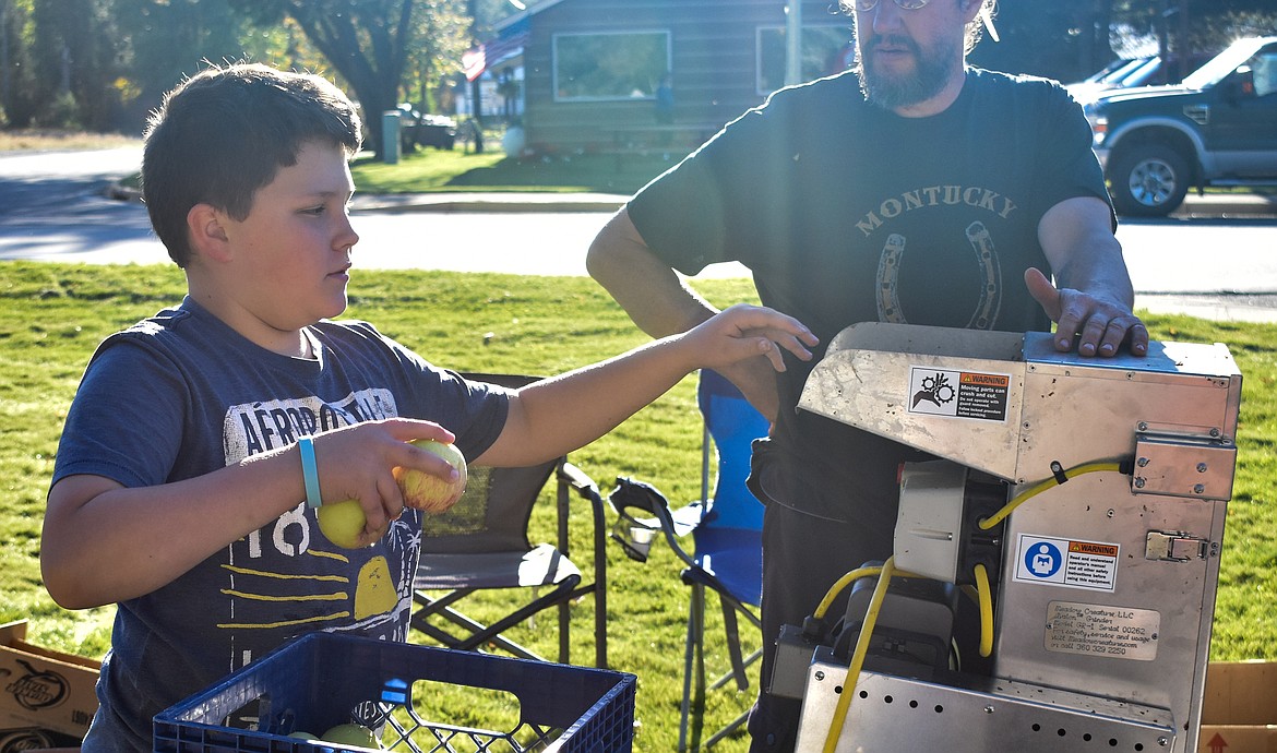 Nicholas Silbermann loads apples into the press Friday at the Troy Farmer&#146;s Market Apple Festival. Silbermann said it was the second year his family has brought their apples to press, and he particularly enjoys the apple cider mixed with pear cider. (Ben Kibbey/The Western News)