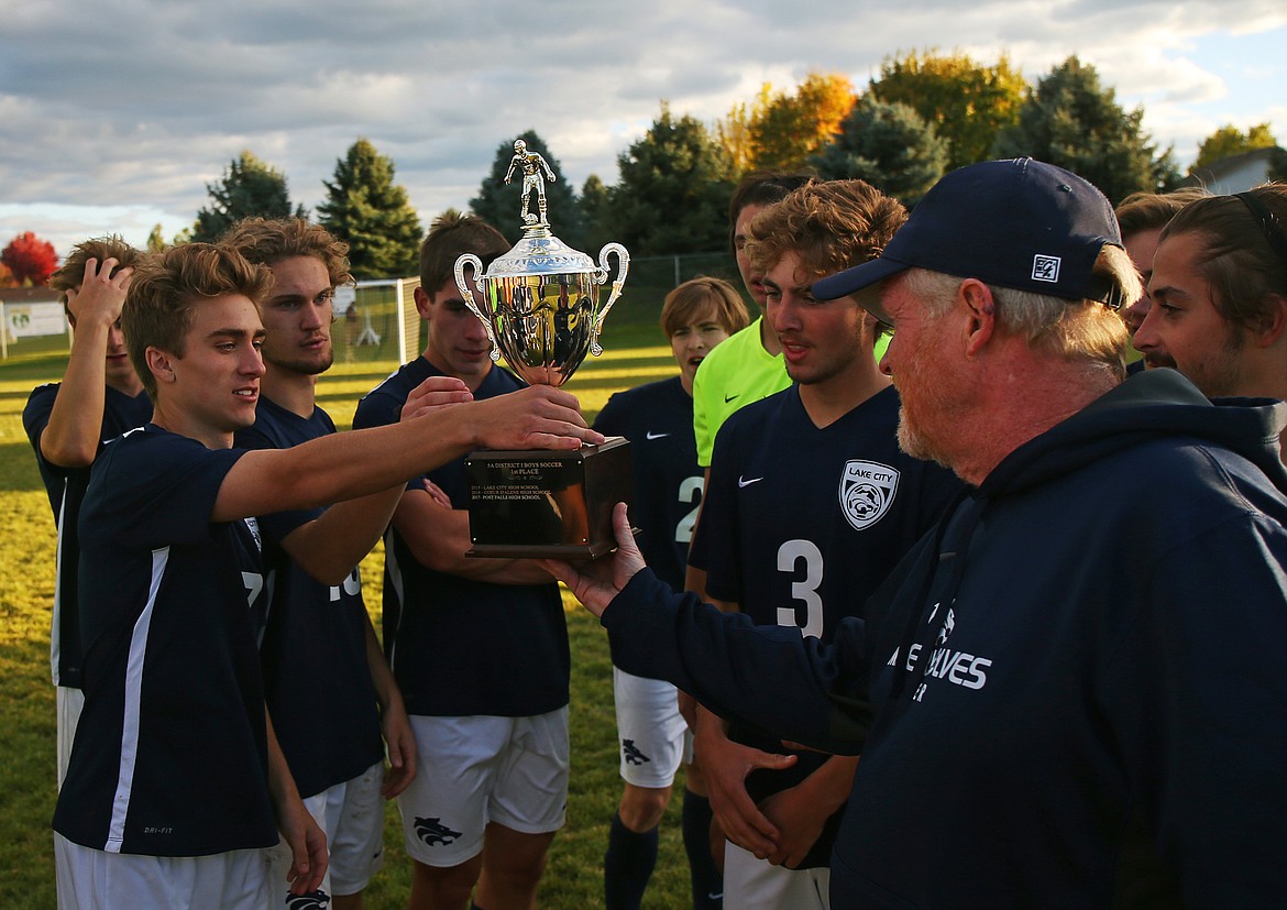 LOREN BENOIT/Press
Lake City boys soccer coach Alan Rich hands the 5A Region 1 championship trophy to Spencer Messina, left, and the rest of the squad after they defeated Coeur d&#146;Alene 3-0 on Oct. 10 at the Irma Anderl Soccer Complex. Lake City (13-2-0) opens the state 5A tournament against Boise (16-2-1) today at 1 p.m. PDT at the Idaho Falls Soccer Complex.