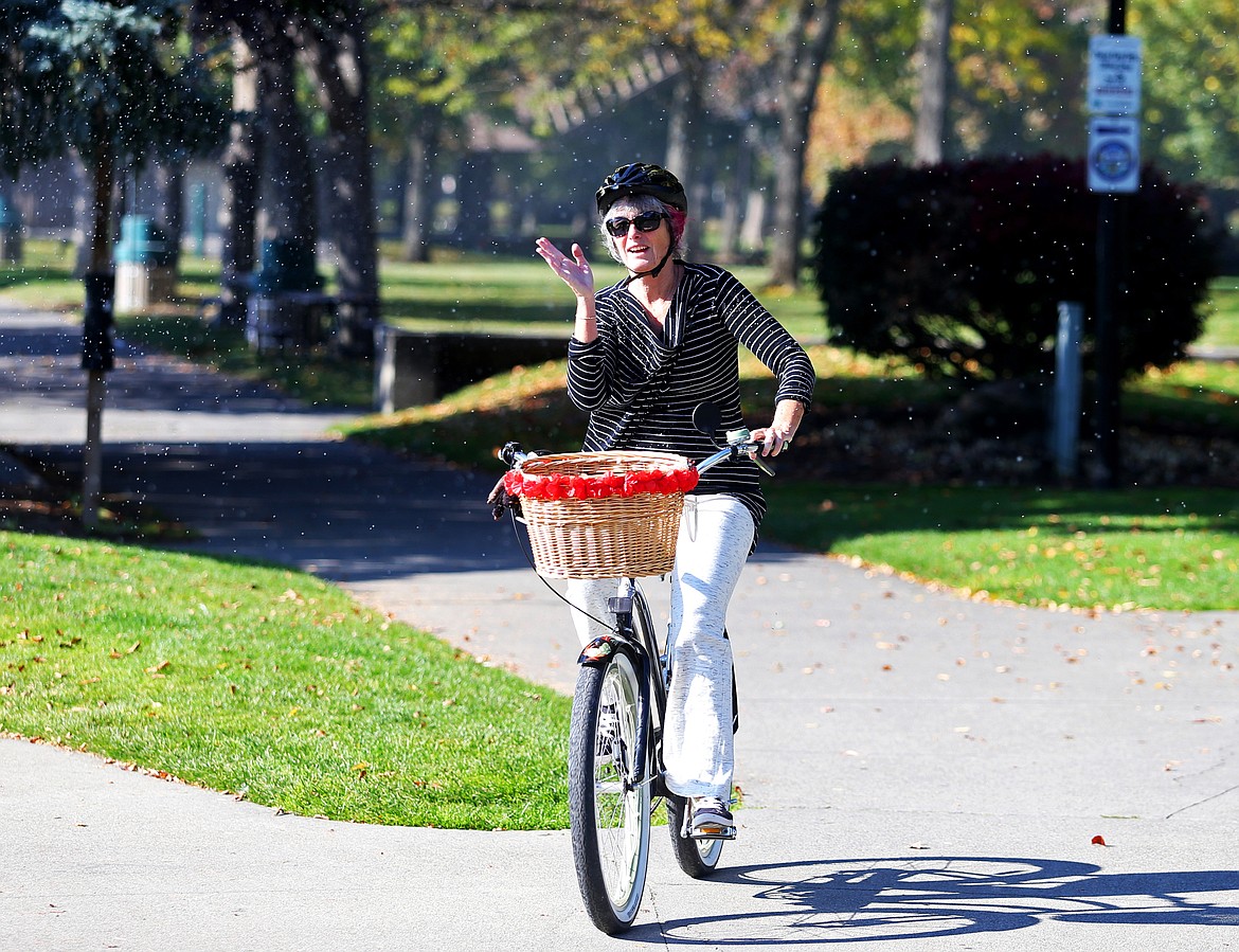 Leslie Andrysiak swats away aphids as she rides her bike through City Park on Wednesday. (LOREN BENOIT/Press)