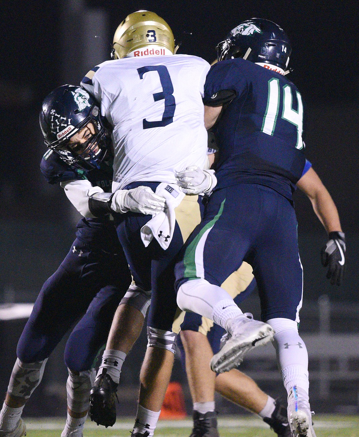 Glacier defenders Gator Mostek (11) and Christian Hensley (14) hit Missoula Big Sky quarterback Draven Lincoln (3) in the second quarter at Legends Stadium on Thursday. (Casey Kreider/Daily Inter Lake)