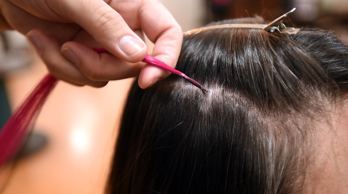 Andrea Marron of En Vogue Salon in Columbia Falls gives Jill Von der Ahe 's dark hair a bright pink extension on Monday, October 15, as part of a benefit for Breast Cancer Awareness month. Ironically, Jill came to the salon immediately following a mammogram exam. The fundraiser continues through October and hair extensions are $10 each. Last year the Salon raised over $3000.(Brenda Ahearn/Daily Inter Lake)