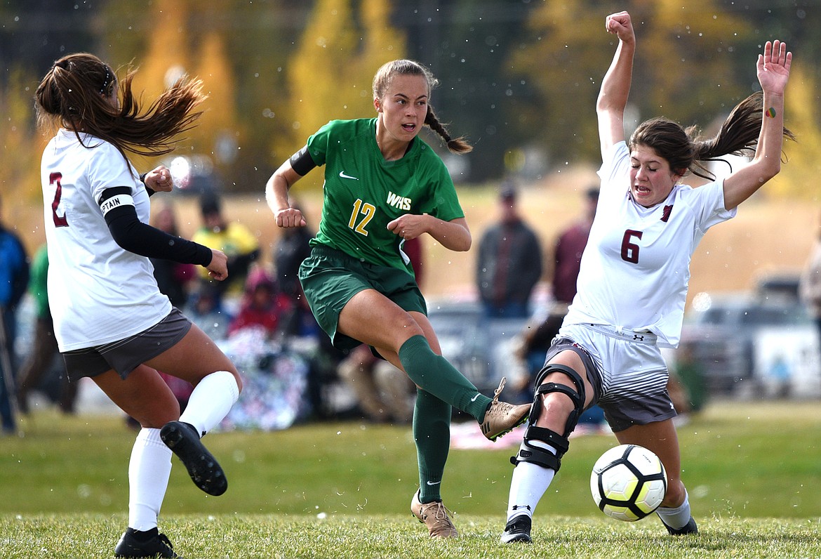 Whitefish's Anna Cook (12) sends a shot on goal between Hamilton defenders Olivia Zepeda (2) and Morgan Brenneman (6) at Smith Fields in Whitefish on Saturday. (Casey Kreider/Daily Inter Lake)