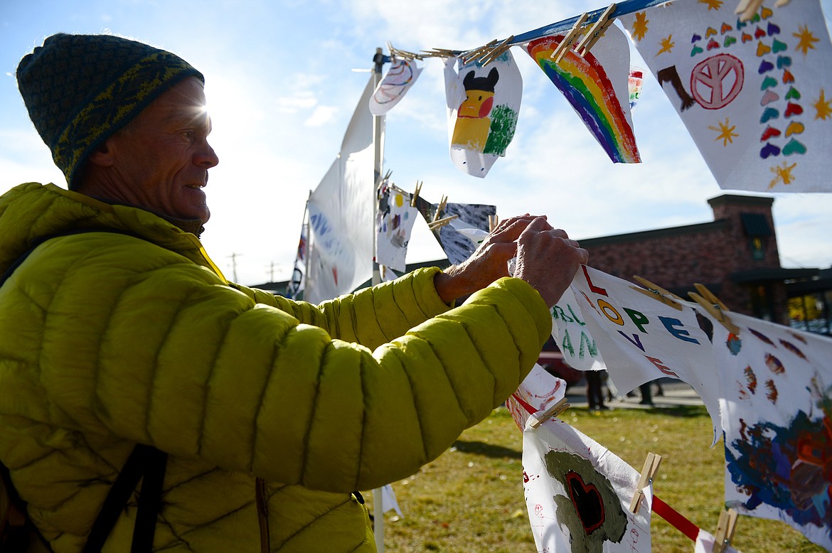 Tim Strand, of Whitefish, hangs a small banner that reads &#147;Fan of Public Land&#148; at Montana Undivided: A Rally for Human Rights and Public Lands at Depot Park in Whitefish on Saturday. (Casey Kreider/Daily Inter Lake)