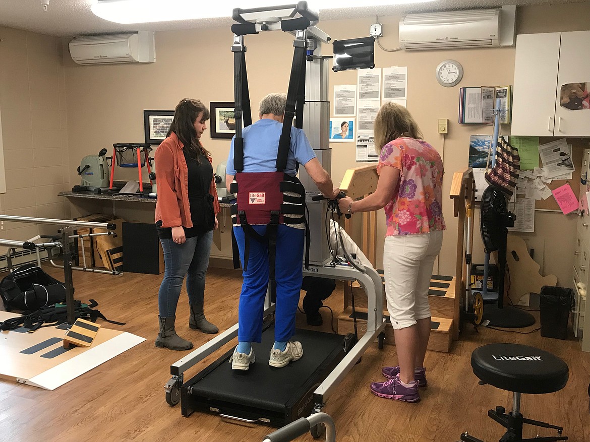 Christina Masterson (left) and Sheri Zumstein (right) superviser Robin Adams as she walks on a treadmill with the help of the LiteGait device.