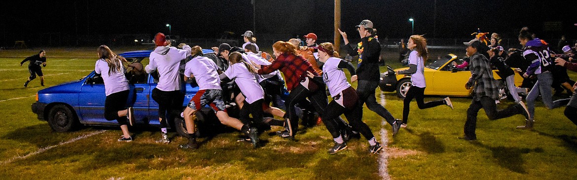 Keeping ahead of the senior class, the Troy High School juniors push their car across the football field during Homecoming Game Night at the football field in Troy Wednesday. The juniors won the relay, but the seniors ultimately won the game night. (Ben Kibbey/The Western News)