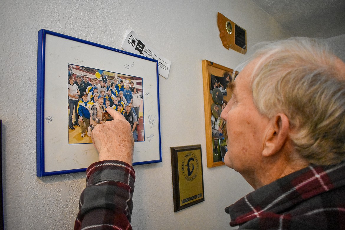 Harvey Frederickson points out wrestlers on the 2003-2004 &#145;A&#146; Western Divisional Champion Libby High School wrestling team, including multiple state champions. The picture with Greenchain wrestler signatures around the frame hangs in the upstairs hallway at his Happys Inn home. (Ben Kibbey/The Western News)
