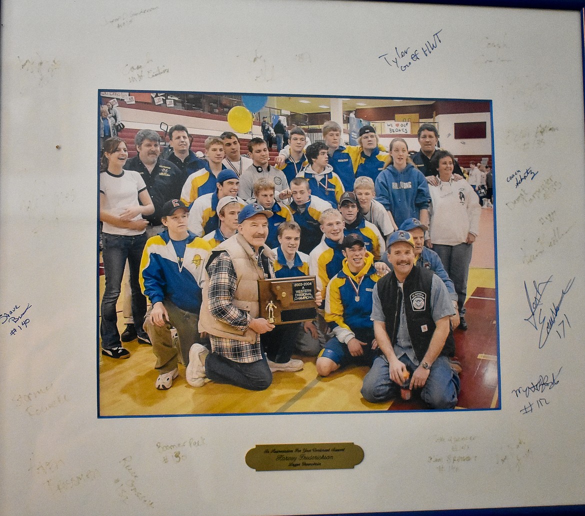 A picture of the 2003-2004 &#145;A&#146; Western Divisional Champion Libby High School wrestling team given to Harvey Frederickson, who holds the plaque and is joined by friend Don Madison at the front of the picture. In addition to including their supporters in the picture, the wrestling team signed the frame of the picture they gave to Frederickson. (Ben Kibbey/The Western News)