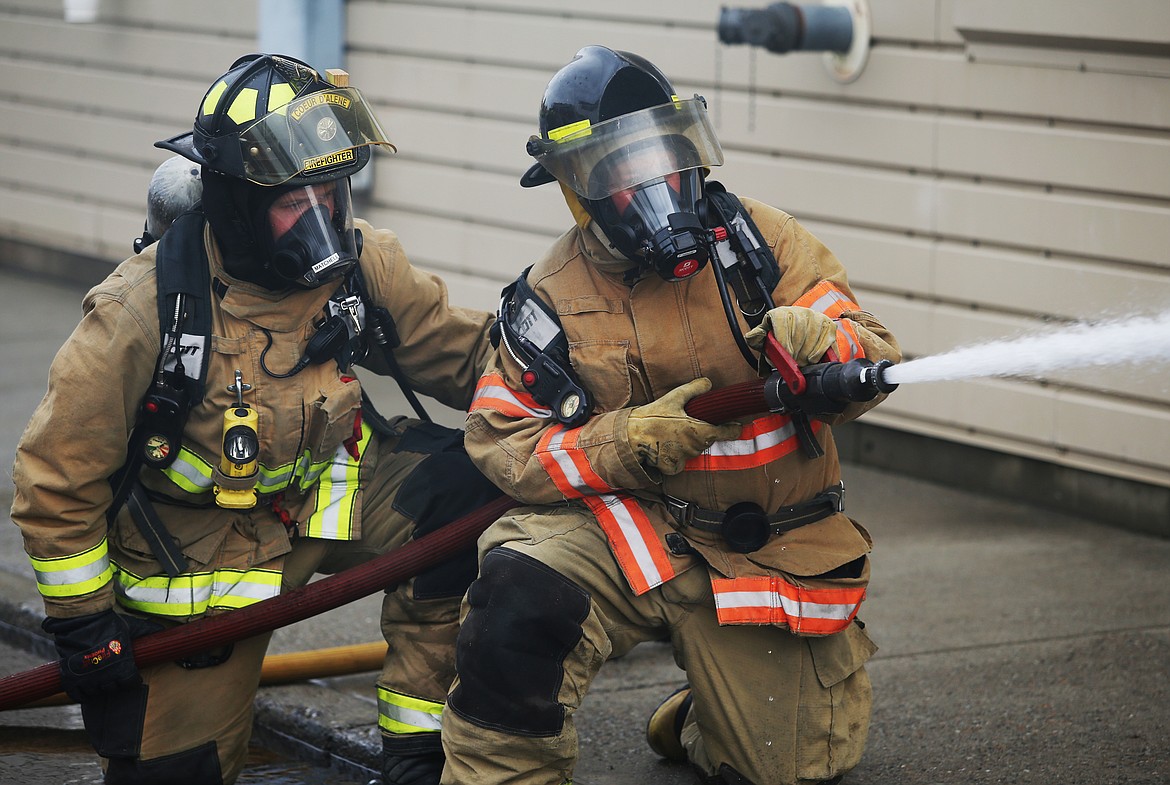 Coeur d'Alene firefighter Chad Matchell, left, helps Coeur d'Alene Press reporter Brian Walker learn how to use a hose before entering a controlled live fire building last Thursday at the Ramsey and Kathleen fire station.  (LOREN BENOIT/Press)