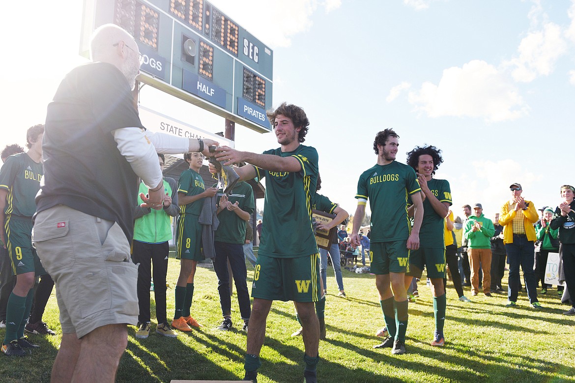 Whitefish's Xander Burger (16) receives a state championship t-shirt from head coach John Lacey after a 6-2 win over Polson at Smith Fields in Whitefish on Saturday. Burger tallied five goals in the game. (Casey Kreider/Daily Inter Lake)