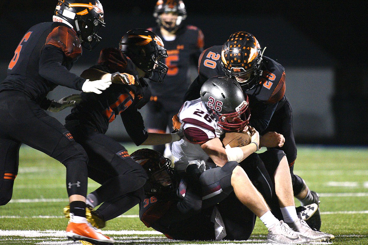 Flathead defenders, from left, Gatlin Bruner (6), Brian Wells (13), Seth Moon (36) and Gunnar Landrum (20) bring down Helena running back Logan Brown (26) on a third-quarter run at Legends Stadium on Friday. (Casey Kreider/Daily Inter Lake)