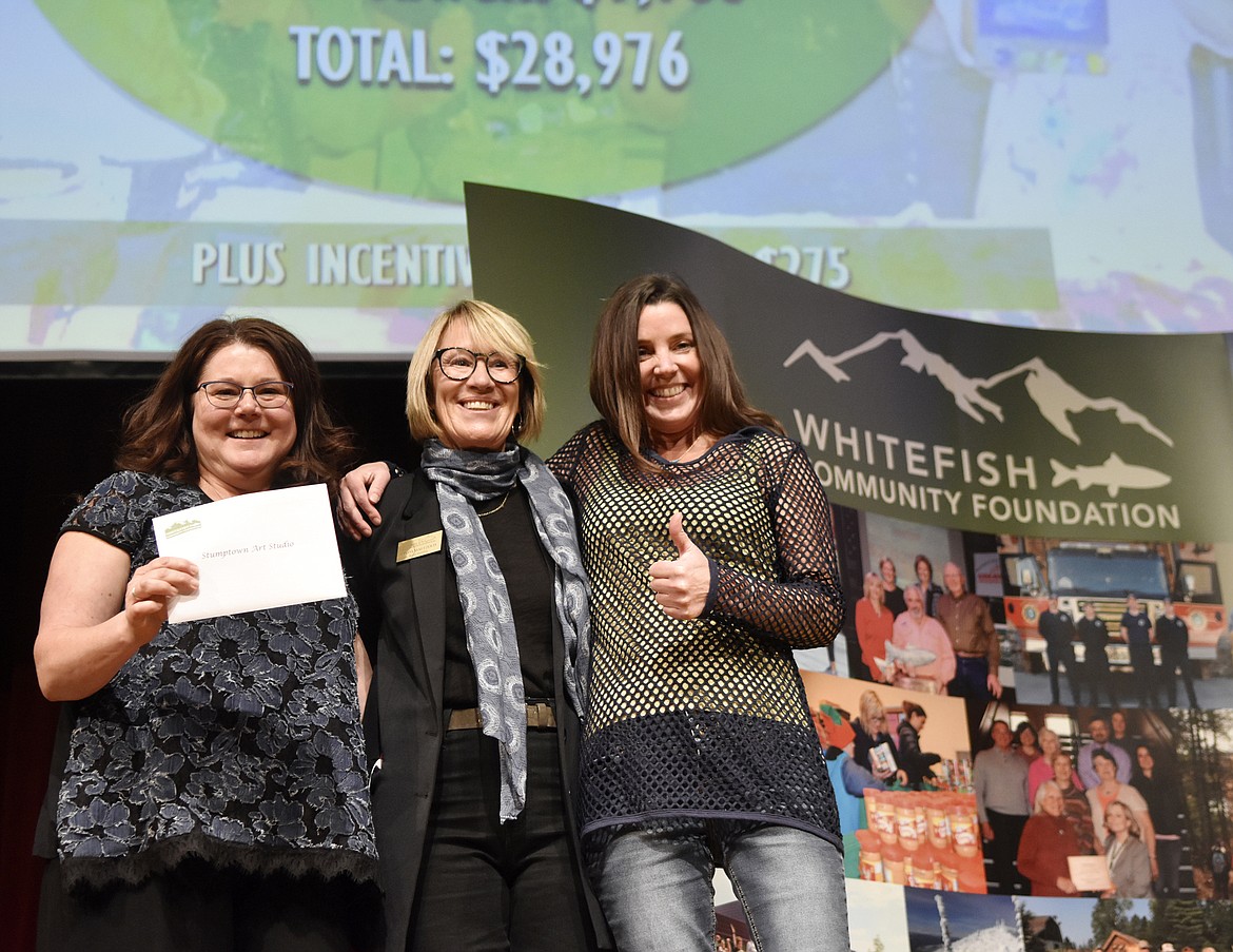 Stumptown Art Studio&#146;s Melanie Drown, left, and Heather Dolan, right, celebrate after accepting a check from Linda Maetzold with the Whitefish Community Foundation during the Great Fish awards ceremony on Thursday at the Whitefish Performing Arts Center. (Heidi Desch/Whitefish Pilot)