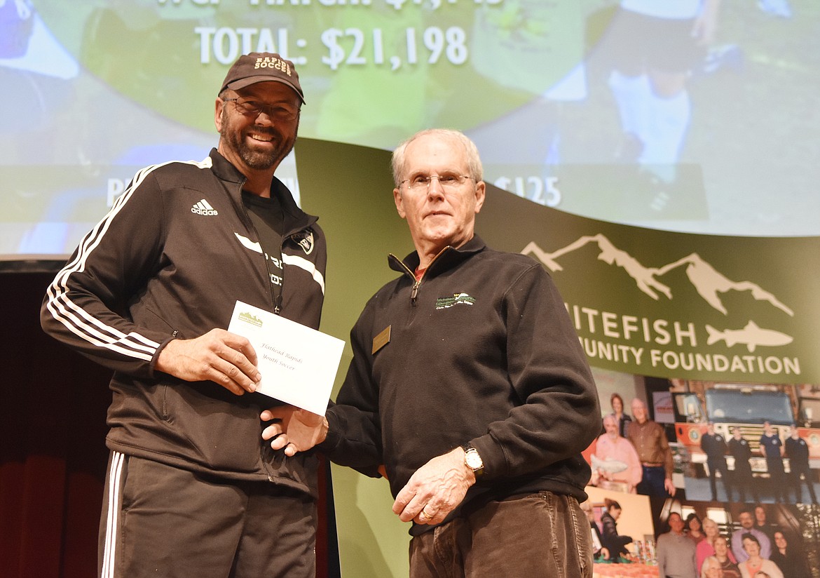 Jay Latimer, with the Whitefish Community Foundation, presents a check to Mark Galbraith, with the Flathead Rapids Thursday during the Great Fish Community Challenge awards at the Whitefish Performing Arts Center. (Heidi Desch/Whitefish Pilot)