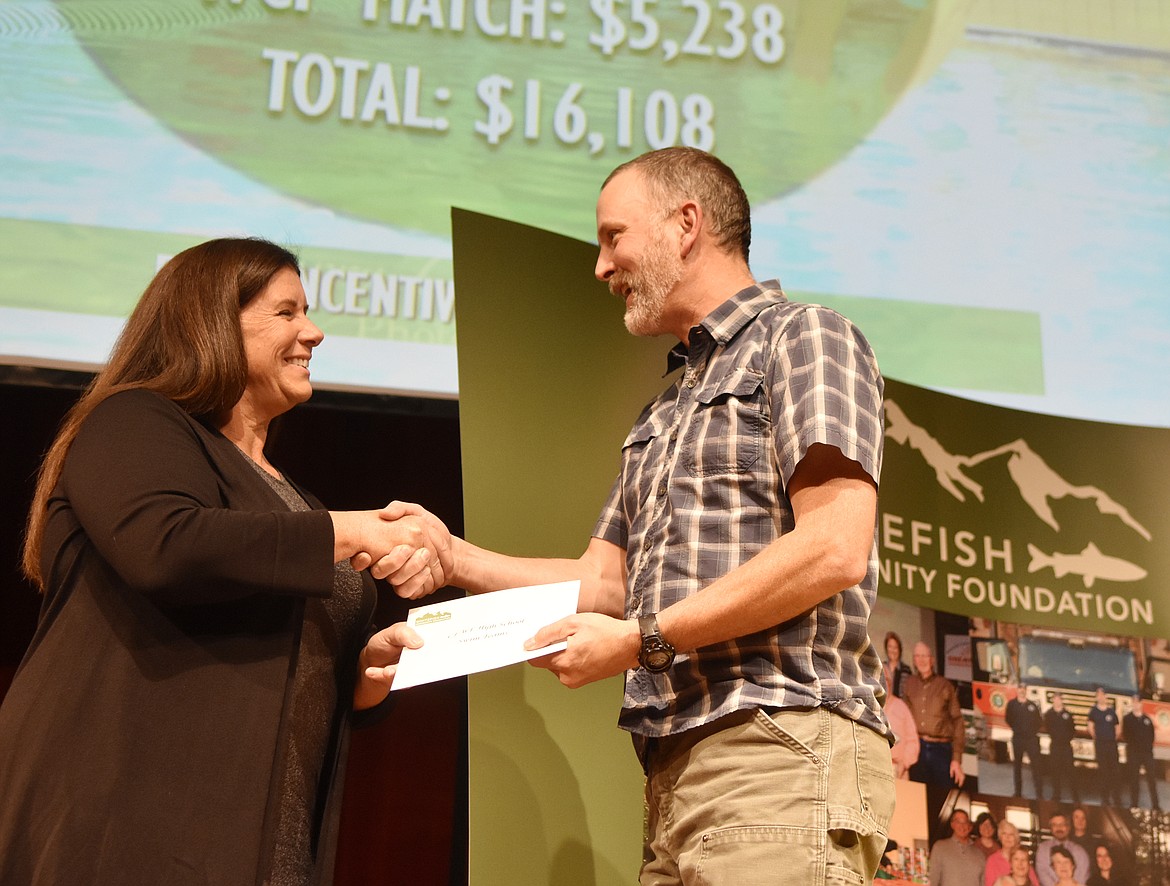 Ellen Moran, board member with the Whitefish Community Foundation presents a check to Dave Ring with the Whitefish-Columbia Falls Swim Team Thursday night during the annual Great Fish Community Challenge awards night at the Whitefish Performing Arts Center. (Heidi Desch/Whitefish Pilot)