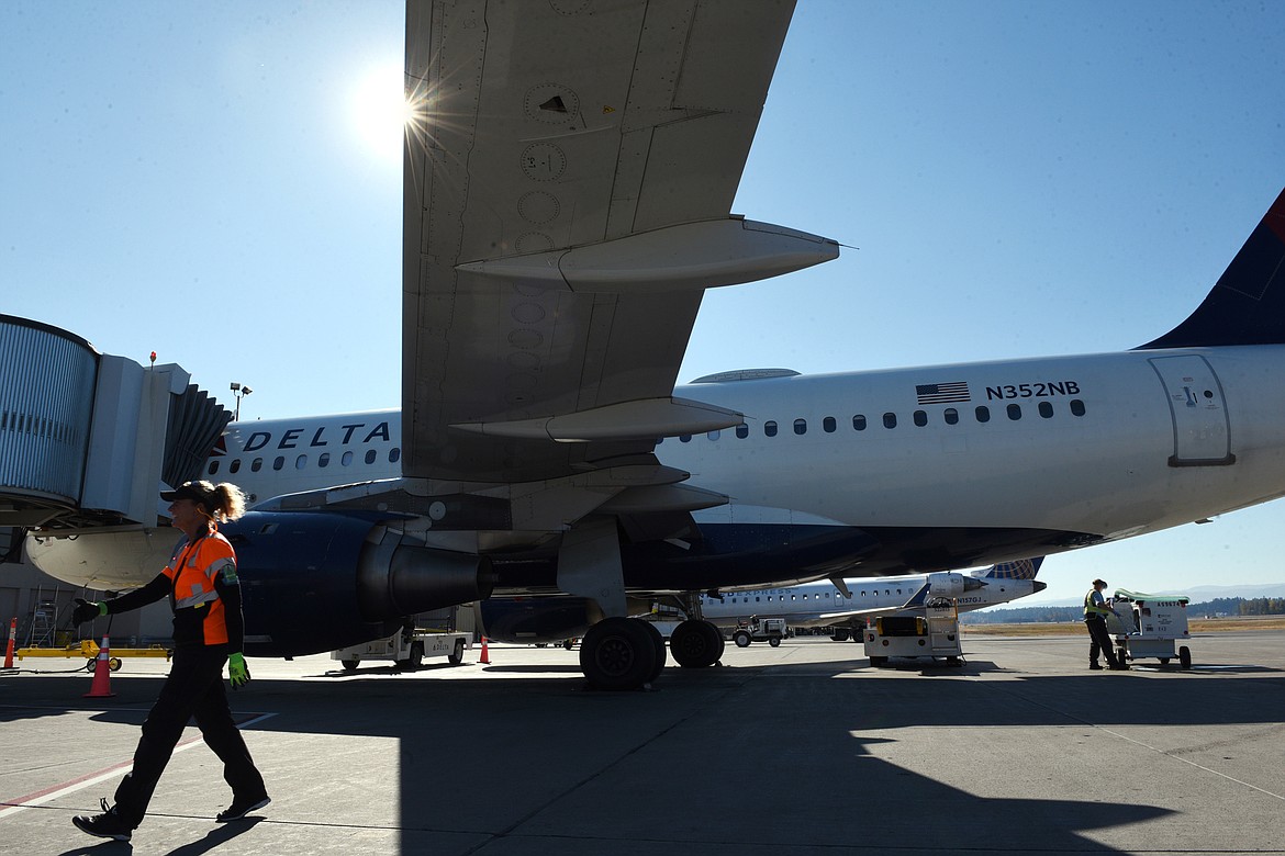 Tammy Smith, of Kalispell, works on the tarmac under a Delta Airbus at Glacier Park International Airport on Wednesday, Oct. 17. (Casey Kreider/Daily Inter Lake)