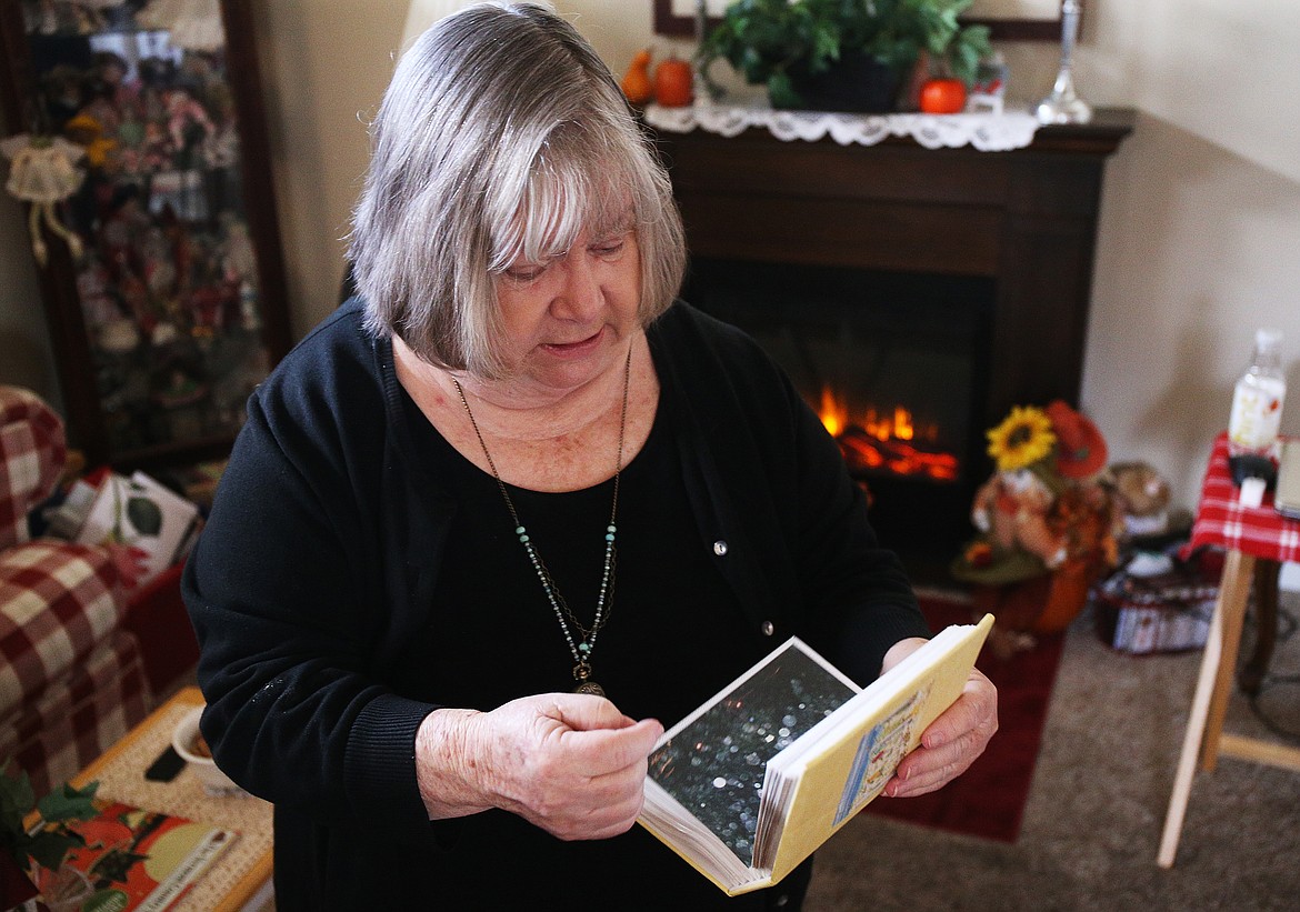 Barbara Norgol flips through an album filled with pictures from a family trip that seem to have captured transparent spheres that paranormal experts refer to as &quot;spirit orbs&quot; that could be manifestations of spirit energy. Norgol, of Post Falls, invited The Press over for a Halloween story about the super creepy images in her fireplace on Tuesday, and shared some other spooky experiences in the process. (LOREN BENOIT/Press)