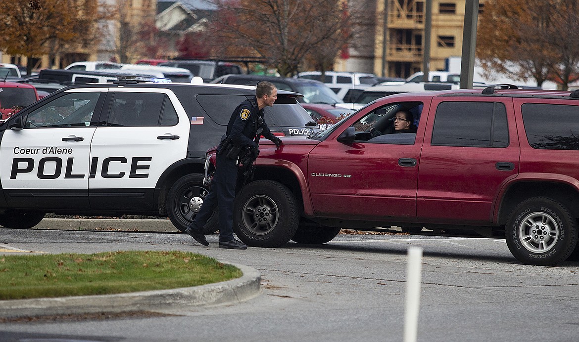 A Coeur d'Alene Police officer talks to a concerned parent at the parking lot entrance to Lake City High School on Tuesday. Officers were called to the high school to investigate a phone call regarding a threat in the parking lot. No weapons were found and no actual threat was identified. (LOREN BENOIT/Press)