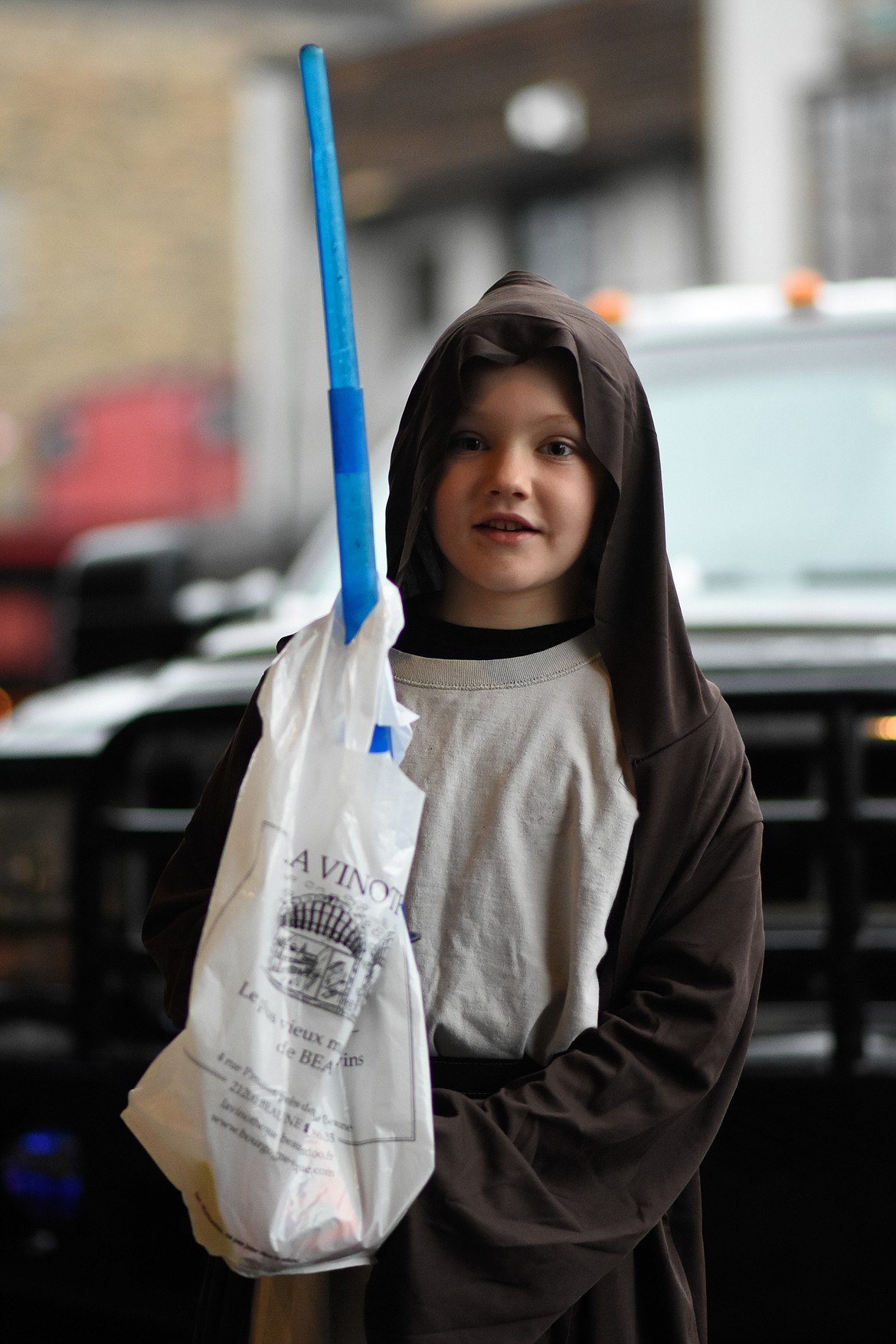 Obi-Wan Kenobi cuts through his bag of candy with his lightsaber in downtown Whitefish during Halloween Wednesday. (Daniel McKay/Whitefish Pilot)