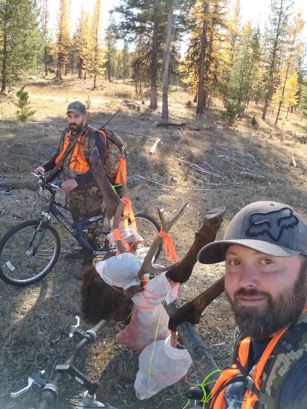 Jimmy Smith, right, and his hunting buddy, Kelly Rooney, show off their unique method of transporting a bull elk Smith bagged Oct. 20 while hunting in Flathead County. The mountain bike method shaved hours of packing time off their journey from the kill site to their vehicle. (Photo submitted)