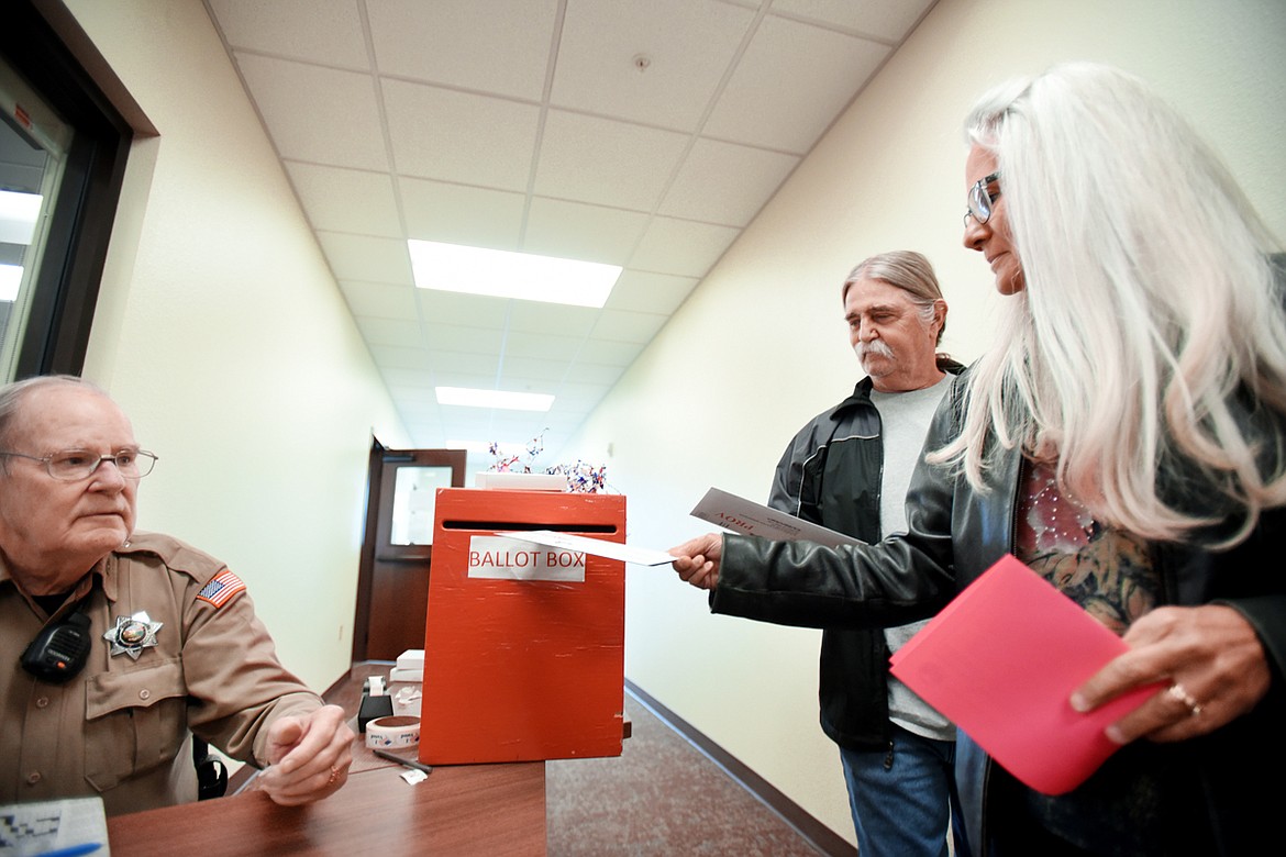 Lori and Terry Droll of Somers voting at the Flathead County Election Department in Kalispell on Tuesday, November 6. On the right is Flathead County Sheriff's Office Posse member Dick deDeaubien, who has volunteered for election day for the past five years.(Brenda Ahearn/Daily Inter Lake)