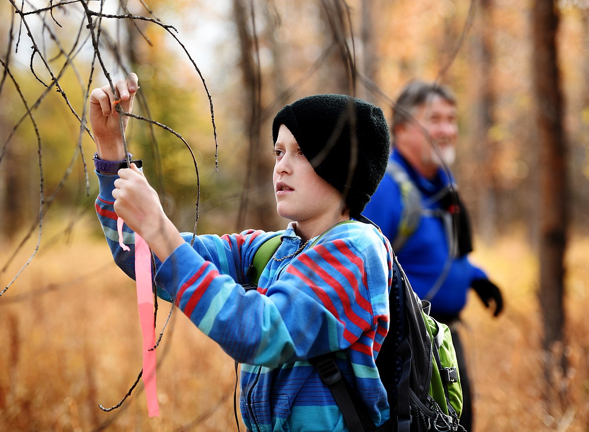 Kalispell Montessori fifth-grader Andrew Jacobson ties a bright orange flag on a branch.