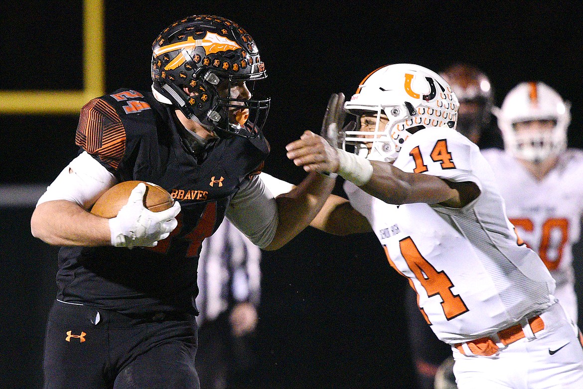 Flathead running back Blake Counts (24) stiff-arms Billings Senior defender Johnnie McClusky (14) on a 48-yard third-quarter run in a Class AA quarterfinal playoff game at Legends Stadium on Friday. (Casey Kreider/Daily Inter Lake)