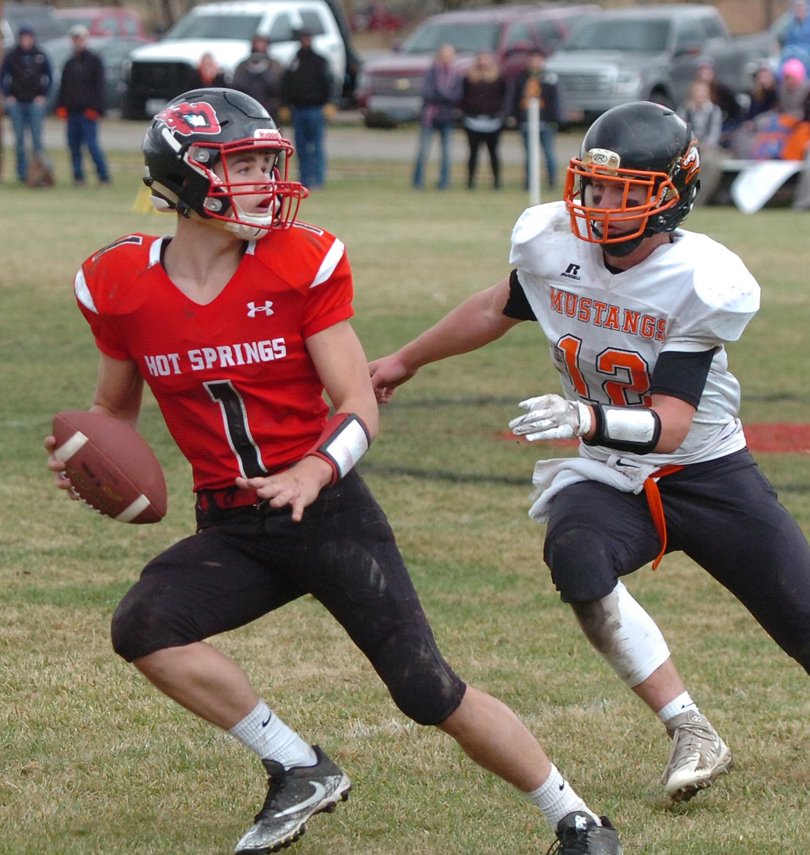 Hot Springs junior quarterback Brandon Knudsen scrambles while being pressured by Keenan Murnion of Jordan during Saturday&#146;s state playoff game. (Joe Sova photos/Clark Fork Valley Press)