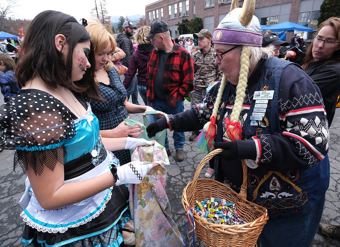 Pam Peppenger, right, hands out candy during trunk-or-treat in the parking lot at the Libby schools administration building Wednesday evening. (John Blodgett/The Western News)