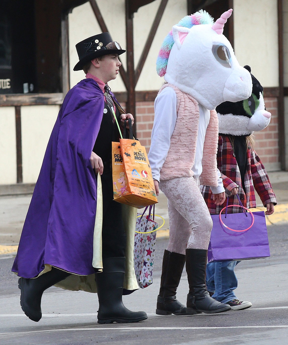 Aaron Thomas as a magician, Olivia Sanderson as a unicorn and Morgan Sanderson as a cat cross Mineral Avenue while trick-or-treating in Libby Wednesday evening. (John Blodgett/The Western News)