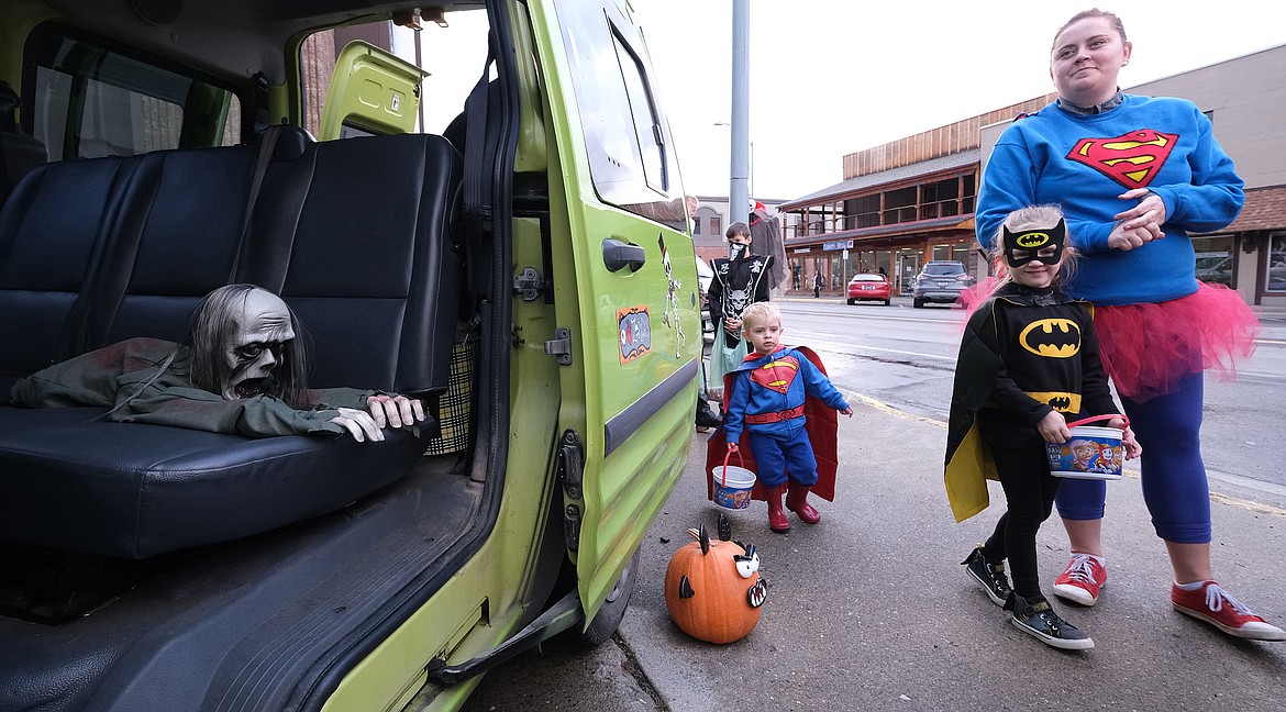 Superman Owen Desch, Batgirl Kayleigh Desch and Supermom Lorenn Desch walk past Lincoln County Transportation&#146;s zombie van while trick-or-treating along Mineral Avenue in Libby Wednesday. (John Blodgett/The Western News)