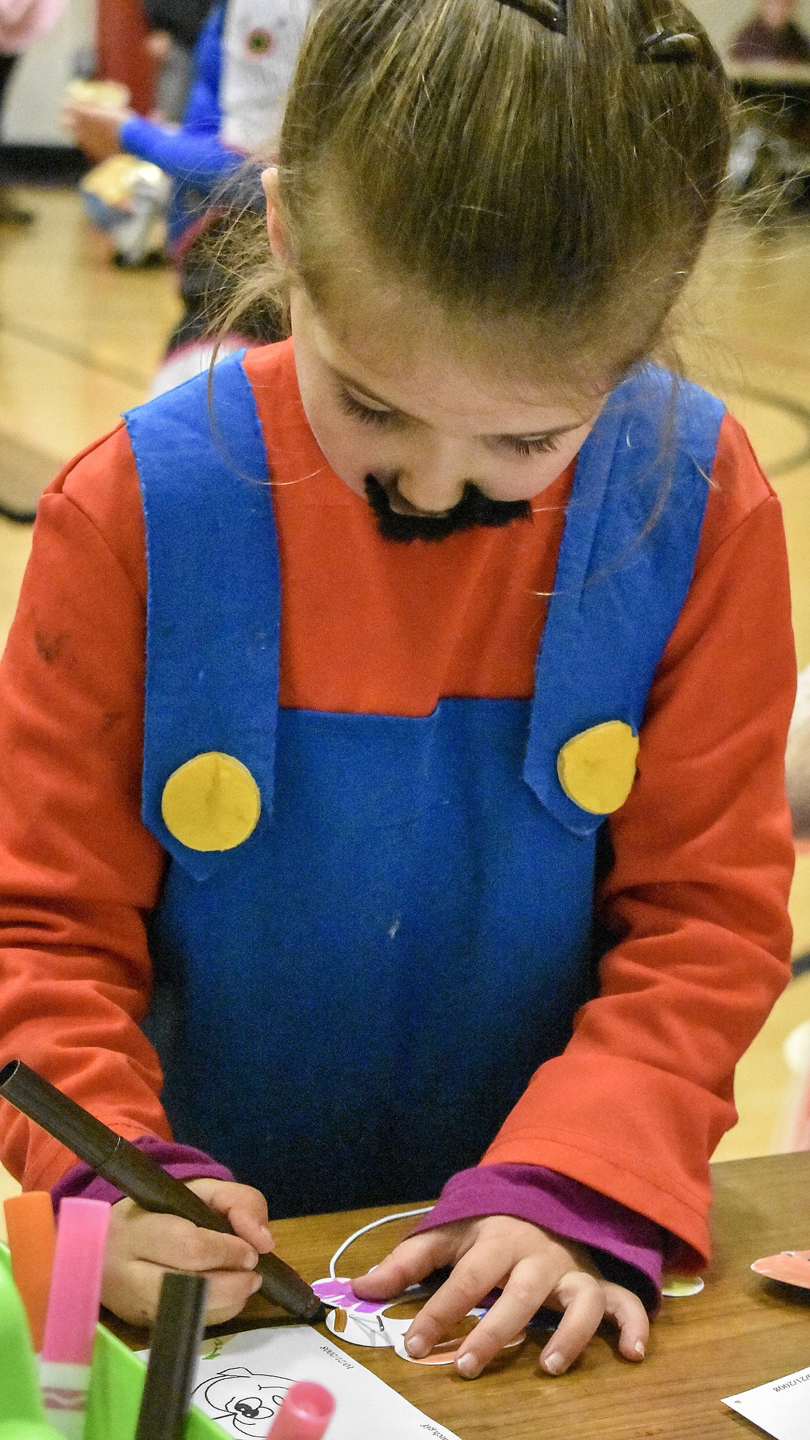 Lyric Stanton has some time away from jumping toadstools to work on a mask at Troy’s W.F. Morrison Elementary during the After School Program Halloween Carnival Wednesday, a part of the ASP’s Lights On After School programs. (Ben Kibbey/The Western News)