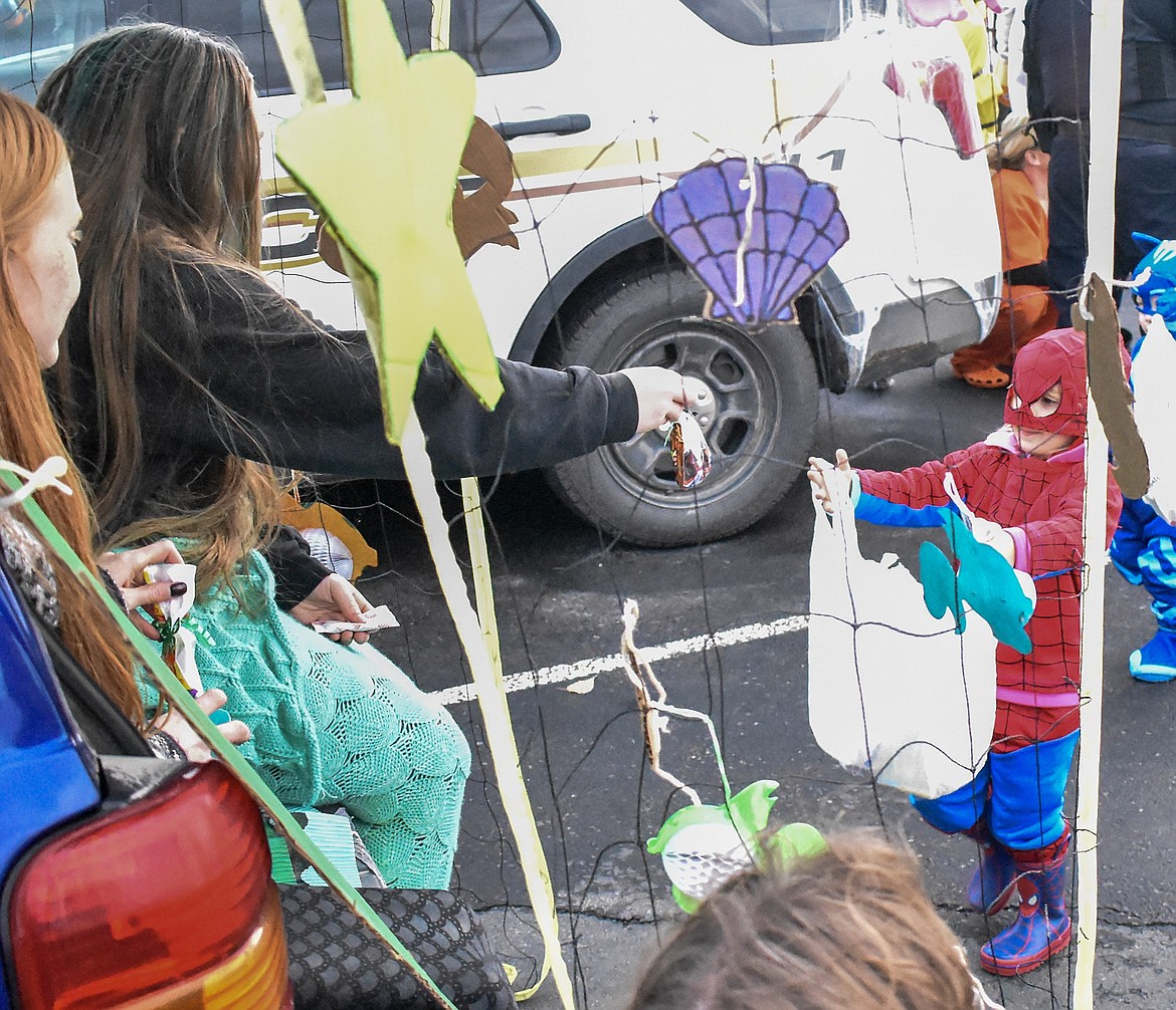 Wren Mcdonald, with Tyne Mischenko close behind, comes with a bag open wide to seek the bounty of the oceans (or at least some candy) from Audrey Evans and Alaiyah Rodgers at Trunk-or-Treat at the Troy Activity Center Wednesday. (Ben Kibbey/The Western News)