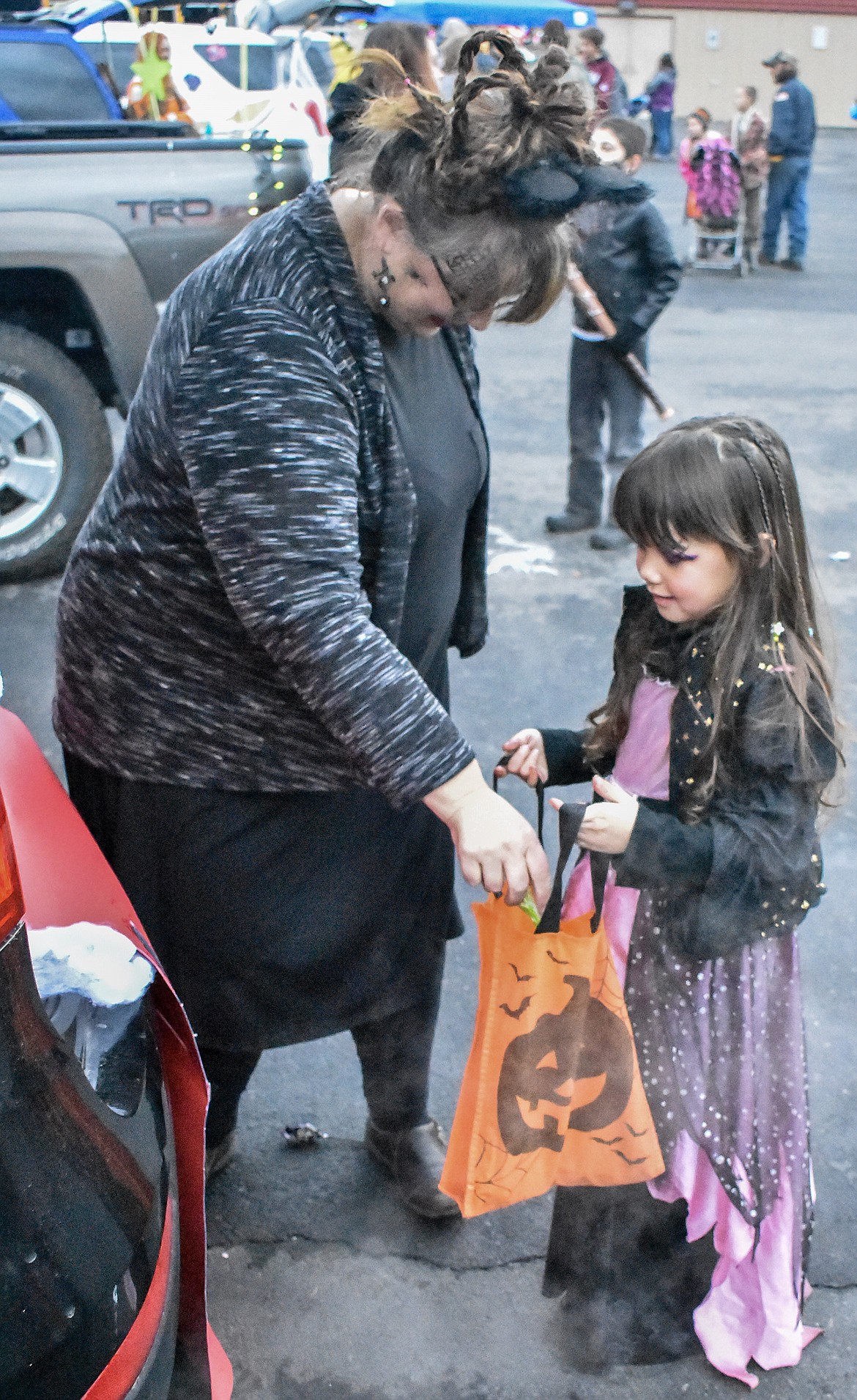 Troy City Clerk/Treasurer Tracy Rebo takes a break from dancing to stay warm to give Avery Wallace candy at Trunk-or-Treat at the Troy Activity Center Wednesday. (Ben Kibbey/The Western News)