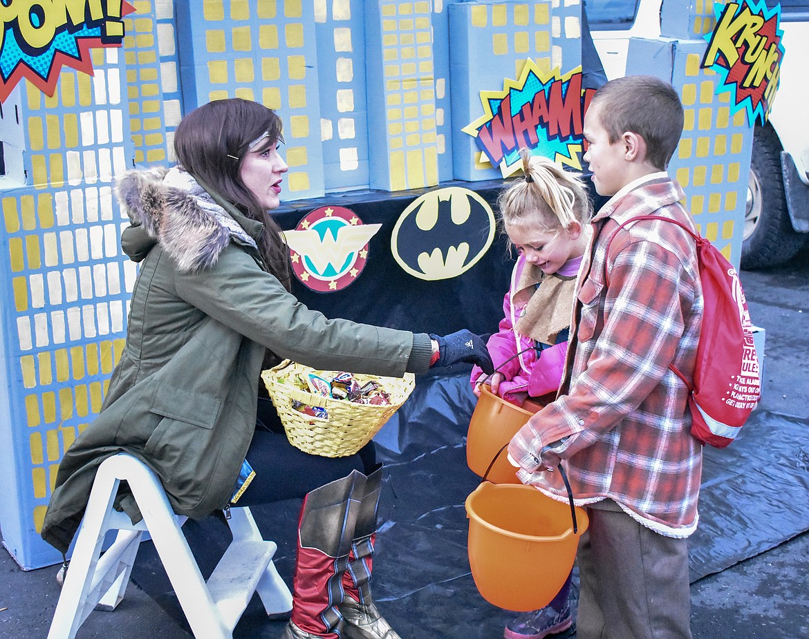 Troy City Judge Robbee Pennock &#151; as Wonder Woman representing the Justice League &#151; has a sidebar with lawyer Hunter Curtis while scarecrow Daizey Curtis checks out her candy at Trunk-or-Treat at the Troy Activity Center Wednesday. (Ben Kibbey/The Western News)
