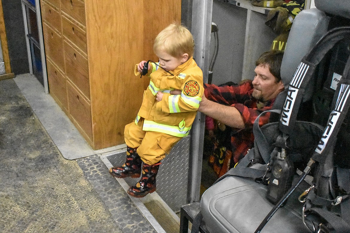 Kayden Hoffman gets a boost from his grandpa, Troy Volunteer Fire Department Assistant Chief Kevin Anderson, during a tour of the department&#146;s apparatus at the Troy Volunteer Fire Department Wednesday. (Ben Kibbey/The Western News)