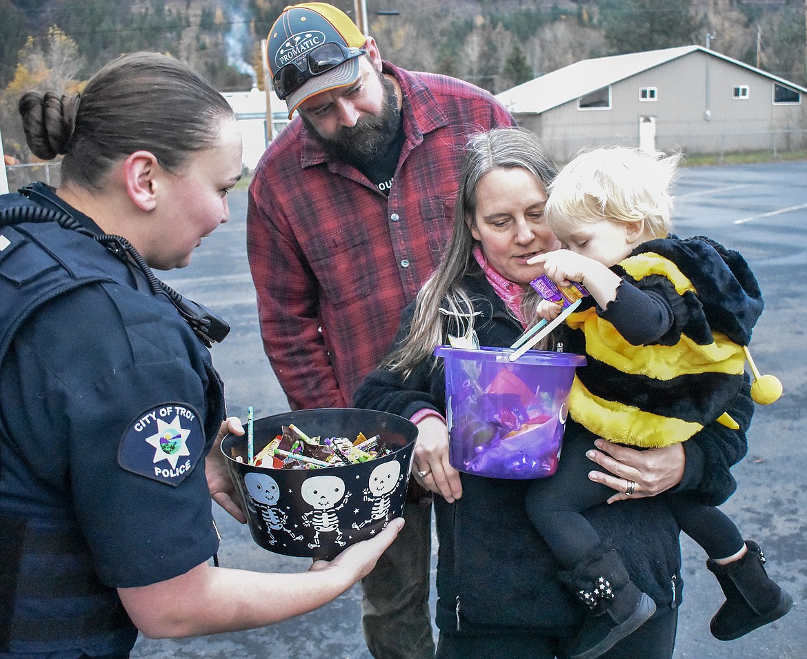 Meghan O&#146;Brien &#151; representing the Troy Police Department, Troy Volunteer Ambulance and Troy Dispatch &#151; helps Riley Hancock with important candy-related matters as Kelly and William Hancock take Riley through the Trunk-or-Treat at the Troy Activity Center Wednesday. (Ben Kibbey/The Western News)