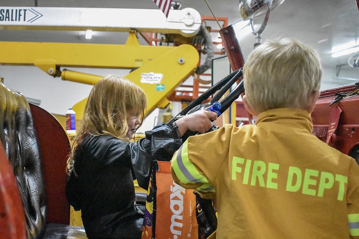 With Kayden Hoffman climbing into the assistant driver&#146;s seat Audrey Towery is ready to roll with the Troy Volunteer Fire Department&#146;s Seagrave fire engine during the department&#146;s Halloween open house Wednesday. (Ben Kibbey/The Western News)