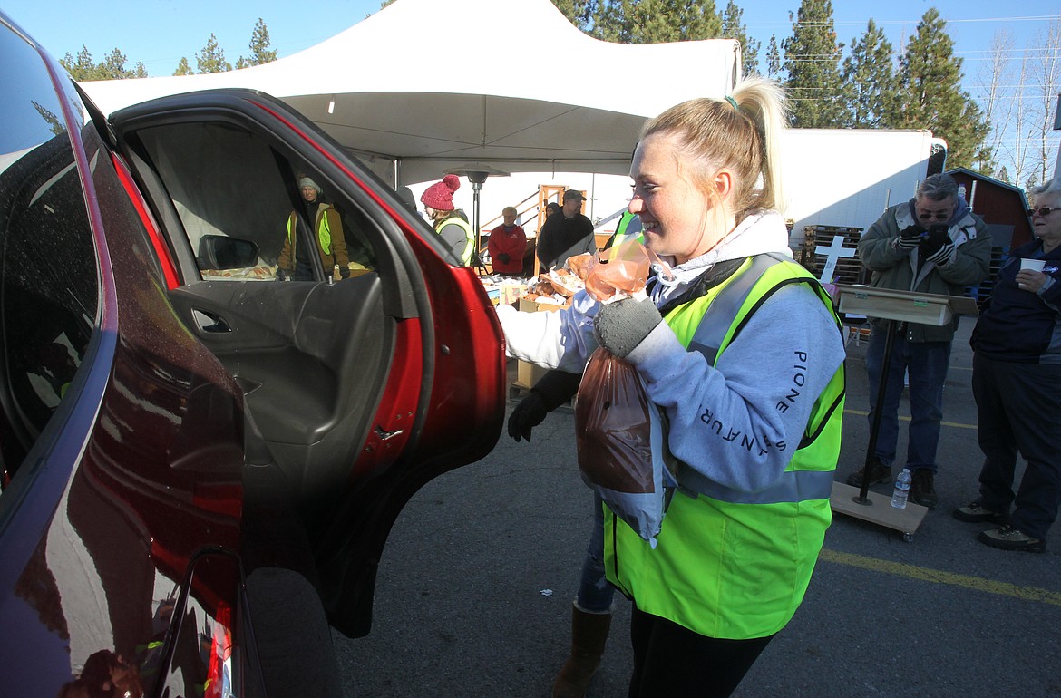 Slick Rock Tanning and Spa employee and Community Action Partnership Coeur d'Alene Food Bank volunteer Hannah Hudson brings a sack of potatoes to a patron Saturday morning during the annual turkey distribution. At least 30 volunteers worked in shifts as they distributed most of the 1,700 turkeys and fixings that will feed local families this Thanksgiving. Distribution continues from 2 to 4 p.m. today. (DEVIN WEEKS/Press)