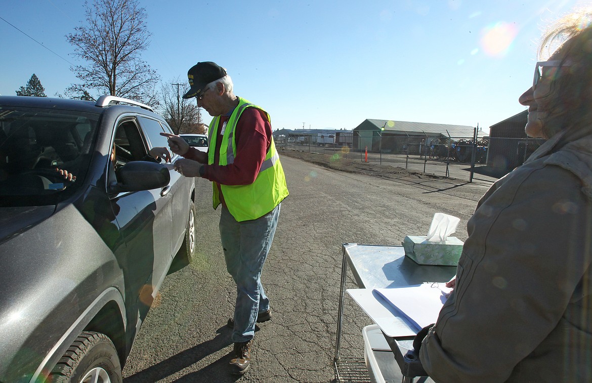 Community Action Partnership Coeur d'Alene Food Bank volunteers Bob Mattfeld and Tammy Rickard collect a pre-registration ticket from a patron Saturday morning during the food bank's annual turkey distribution for Thanksgiving. This year's distribution went quickly and smoothly thanks to the implementation of a new system that assigned pick-up times and required volunteers to place the turkeys, potatoes and fixings in vehicles so people didn't even have to get out of their cars. (DEVIN WEEKS/Press)