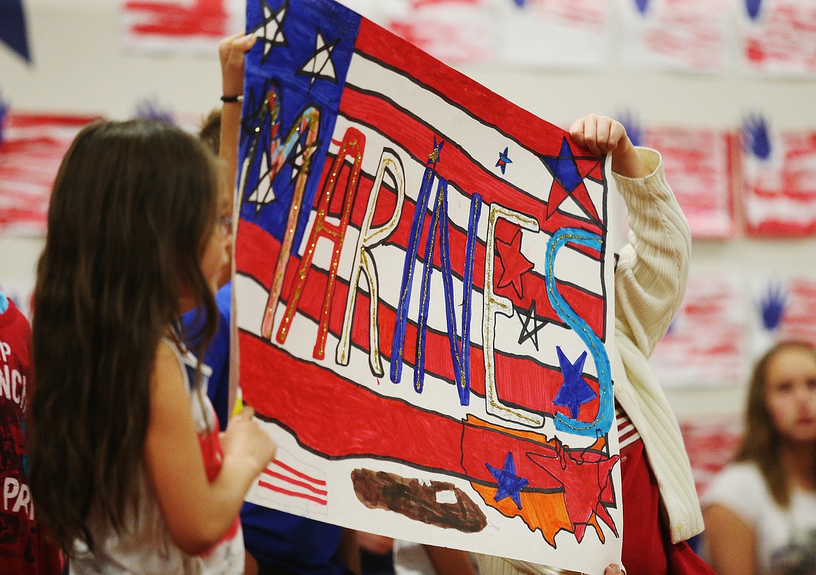 Two students hold up a sign as U.S. Marine veterans stand to be recognized during Spirit Elementary School's Veterans Day assembly on Monday. (LOREN BENOIT/Press)