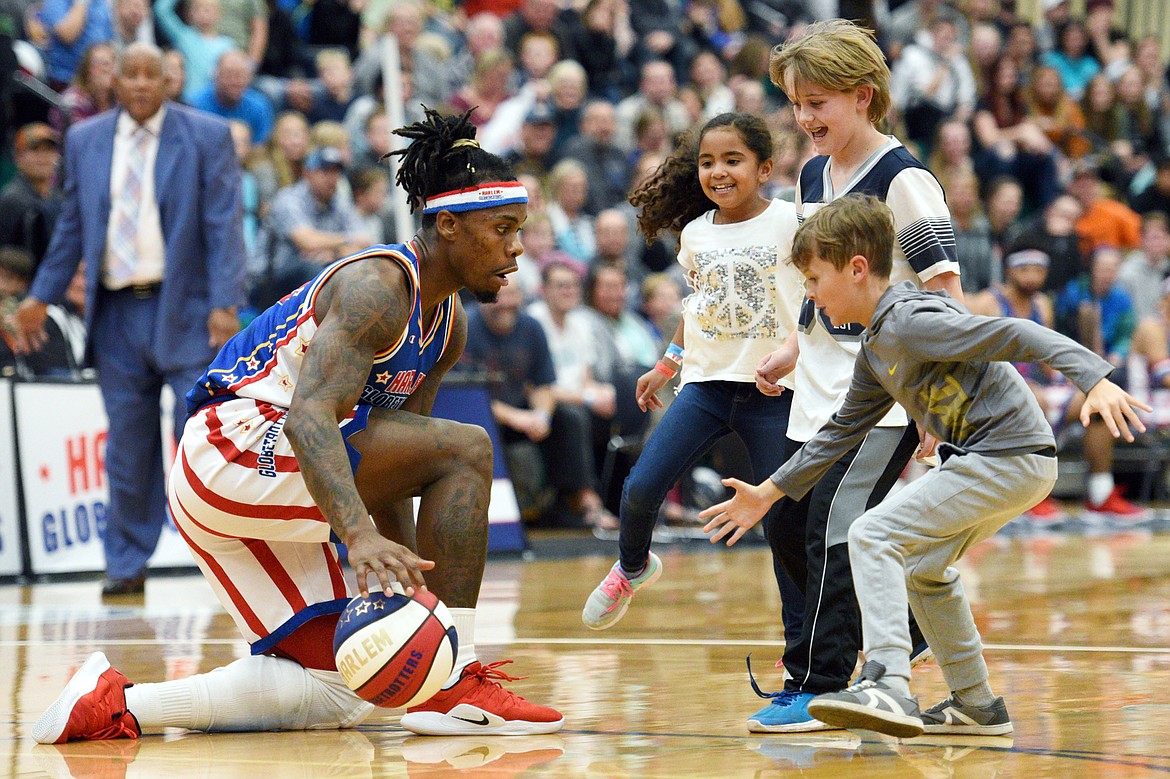 Harlem Globetrotter &quot;Beast&quot; dribbles around a group of children attempting to steal the ball at Glacier High School on Tuesday, Nov. 13. (Casey Kreider/Daily Inter Lake)