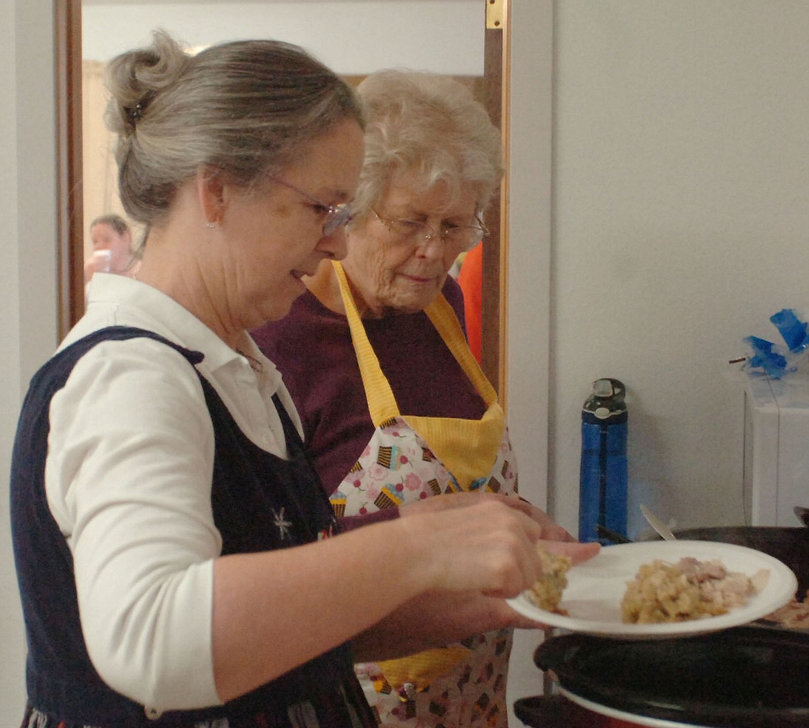 West Shore Community Church members Ann Murphy, left, and Sonya Engbretson prepare a serving of turkey and stuffing during the annual Thanksgiving dinner at the Big Arm Fire Station.