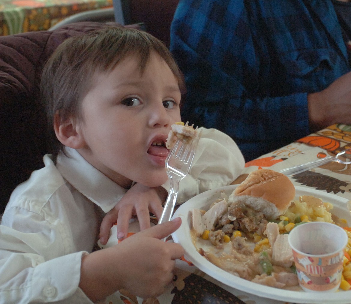 Three-year-old Big Arm resident Aaron Hemeline takes a big bite of delicious turkey during the Thanksgiving dinner last Saturday, hosted by the West Shore Community Church.