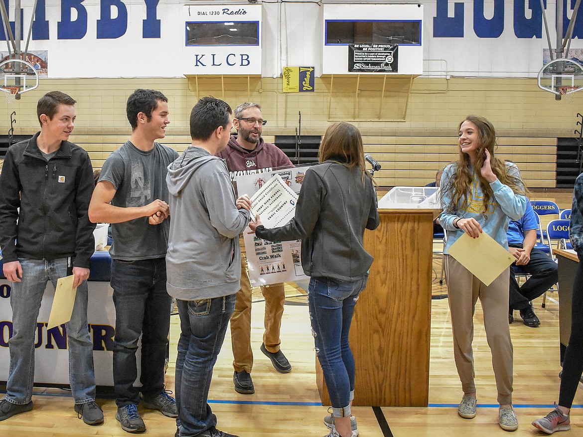 Libby High School cross country Head Coach Rodd Zeiler presents a &#147;Running Strong&#148; poster to sophomore Savannah Sanderson, who received the team award for &#147;Most Improved&#148; during the Fall Awards Assembly Thursday.