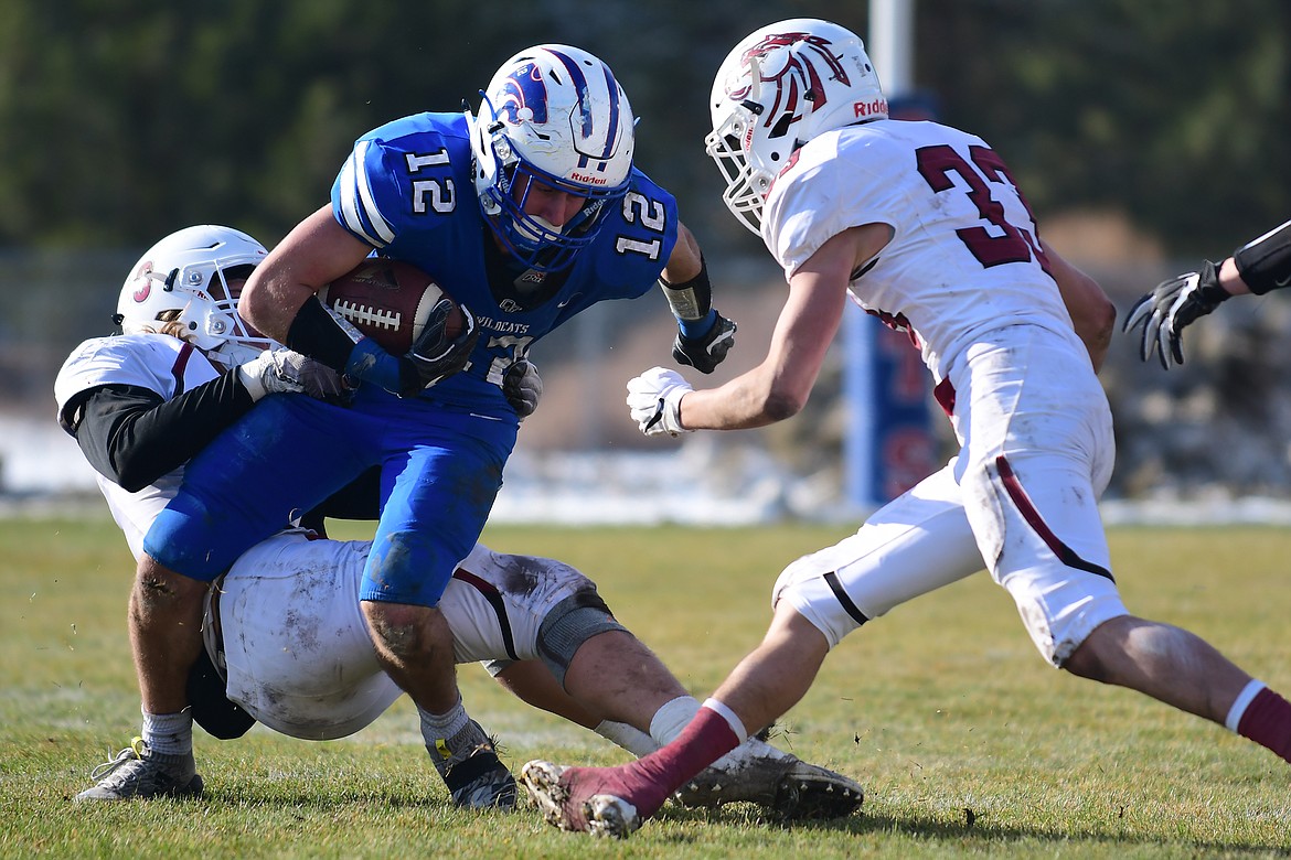 Parker Greene tries to break free from a pair of Hamilton defenders during action at the Class A state semi-final game in Columbia Falls Saturday. (Jeremy Weber photo)