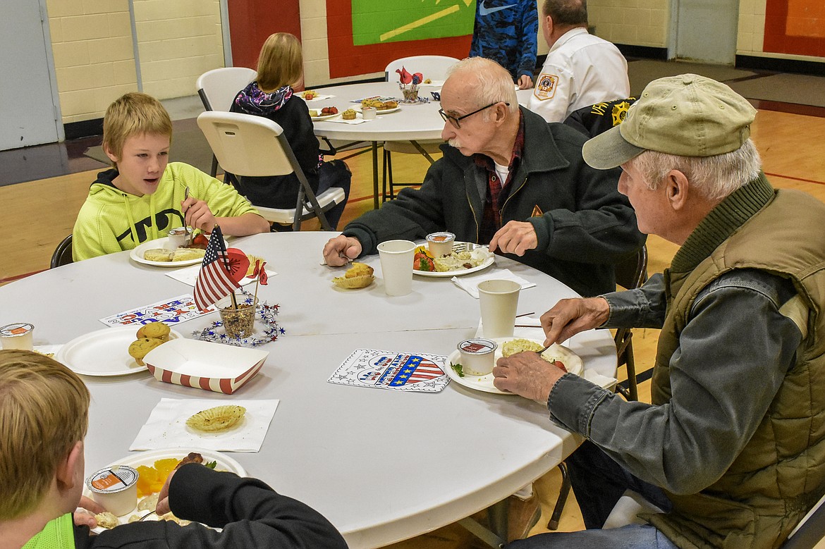 Konnor Mischenko eats and talks with U.S. military veterans Jerry Davis and Dave MacLaughlin during the Veterans Day breakfast at W.F. Morrison Elementary in Troy Monday. Mostly they had been discussing football, the group agreed. (Ben Kibbey/The Western News)