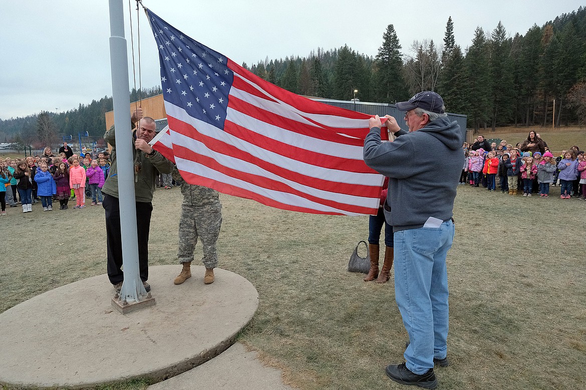 Guests of honor prepare to raise the American flag during a Veterans Day ceremony at Libby Elementary School Monday morning. They are, from left: Tom Gallagher, Tina Resch (obscured), Linda Sverdrup (obscured) and Dan Watkins. (John Blodgett/The Western News)
