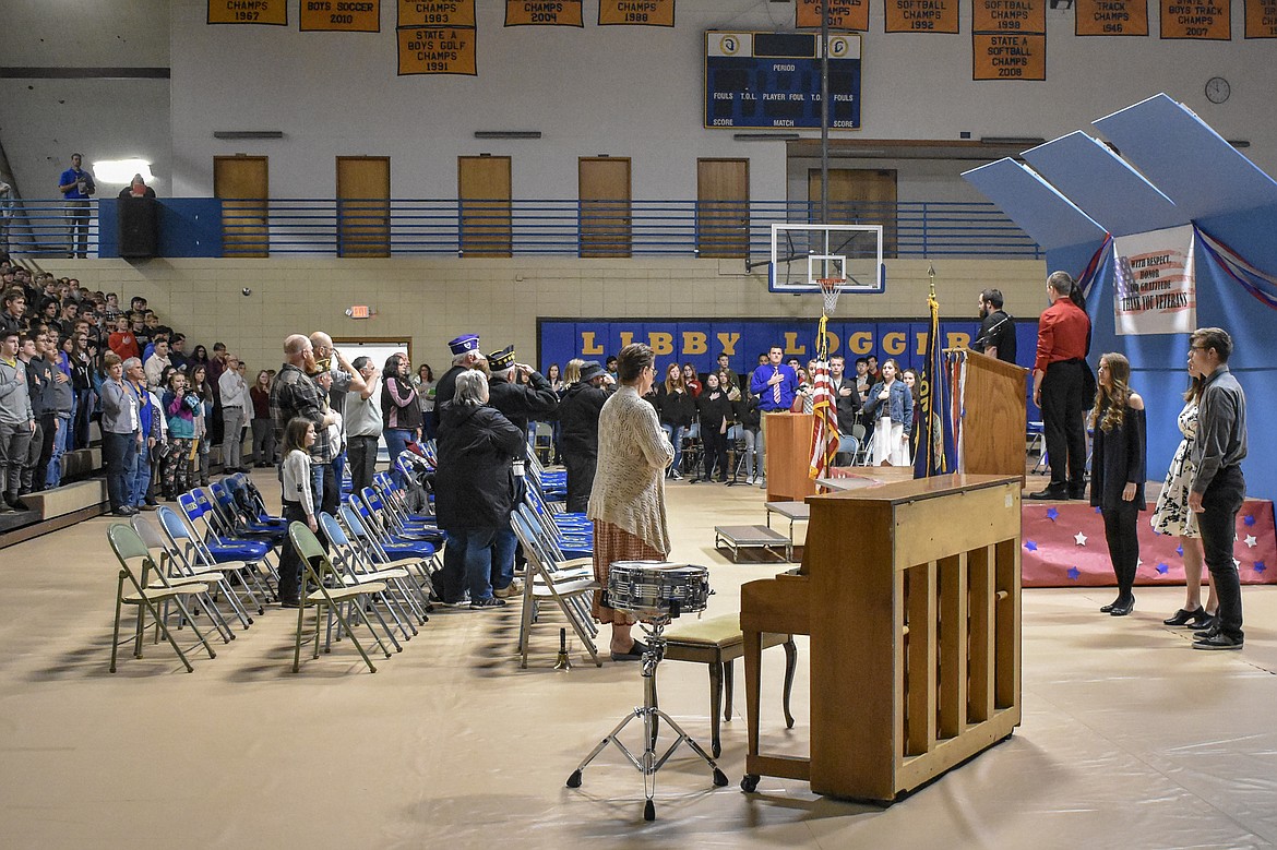 Local veterans, students and community members gather in salute as the National Anthem is performed by Bella Hollingsworth, Mikalyn Zeiler and Kaleb Lingren during the Veterans Day observance in the Ralph Tate Memorial Gymnasium at Libby High School Monday. (Ben Kibbey/The Western News)